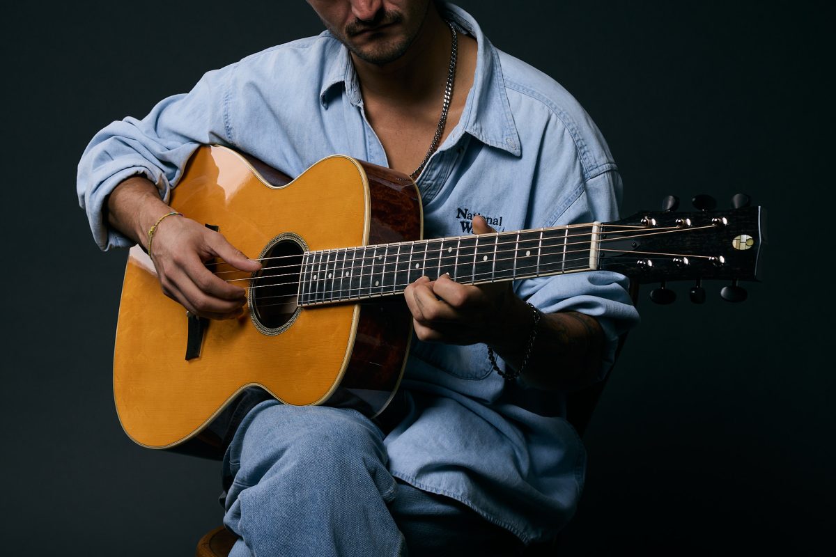 Guitarist playing a Thom Orgler Vajolet (Orchestra Model) acoustic in a studio—close-up of hands, spruce top, fretboard, and headstock.